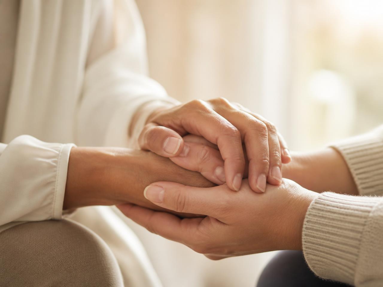 Two people holding hands in a gesture of support and reassurance